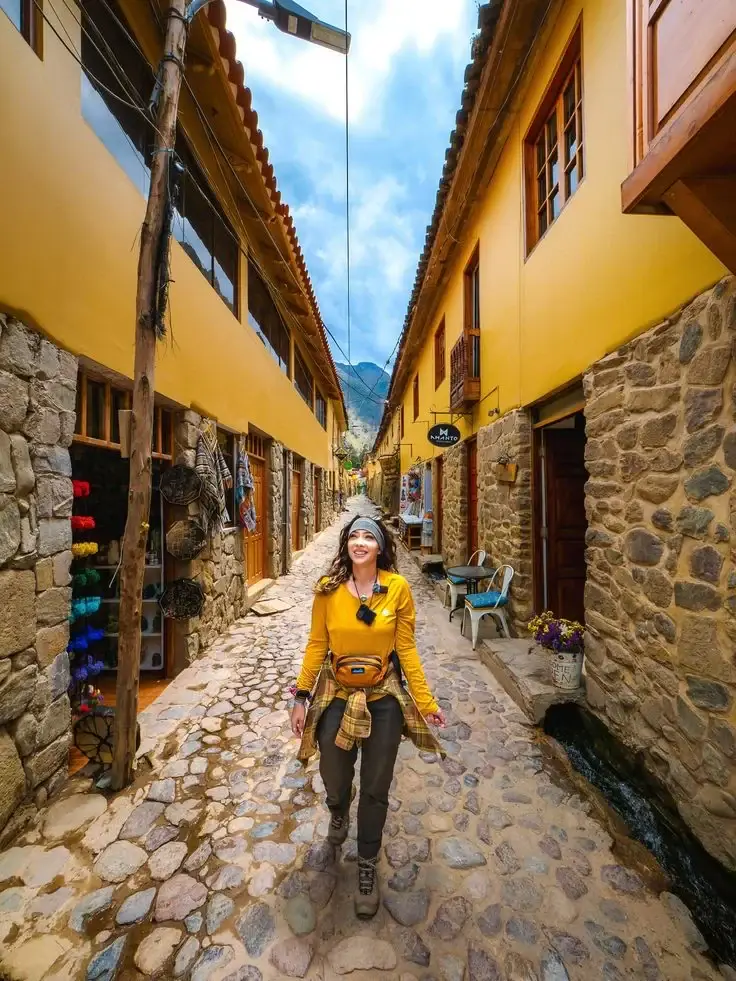 A traveller carrying a camera in a cobbled Cusco street