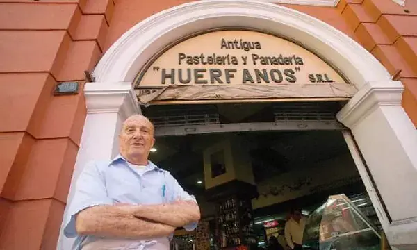 The signed entrance of Antigua Panadería Huérfanos, with an adult man standing outside.
