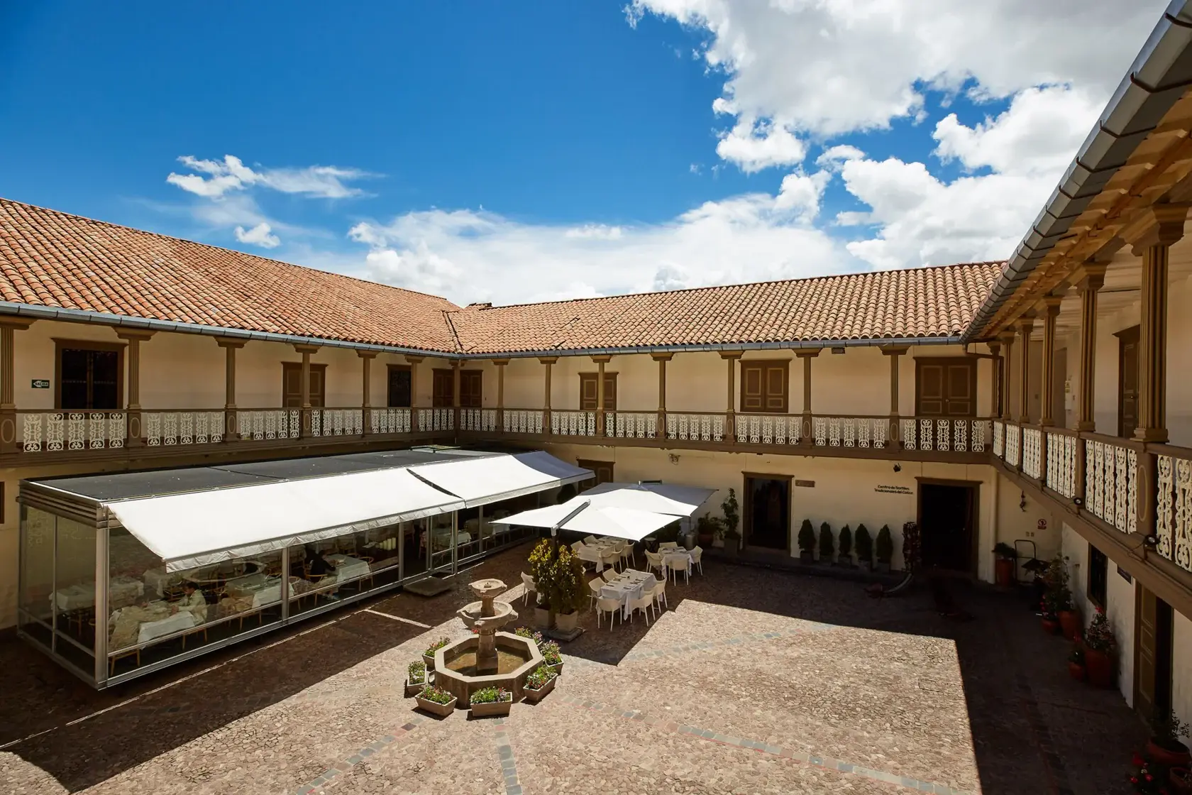 The historic courtyard of the Museo de Arte Precolombino in Cusco, surrounded by stone arcades and tiled roofs.