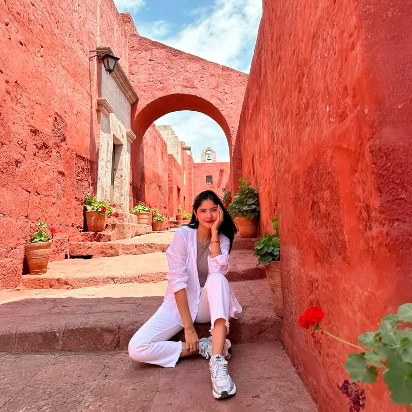 A visitor seated beside the red arches of Santa Catalina