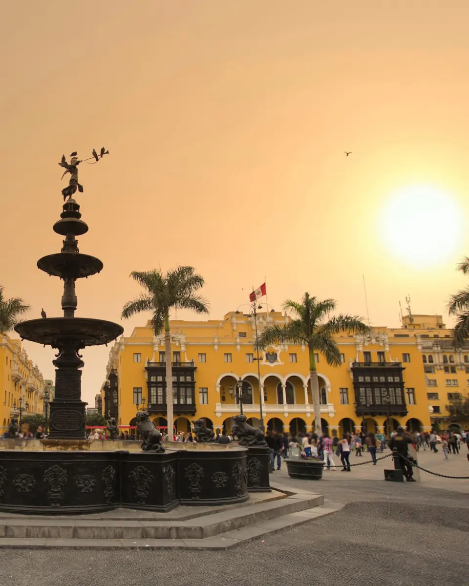The fountain and yellow buildings of Plaza Mayor in warm evening light.
