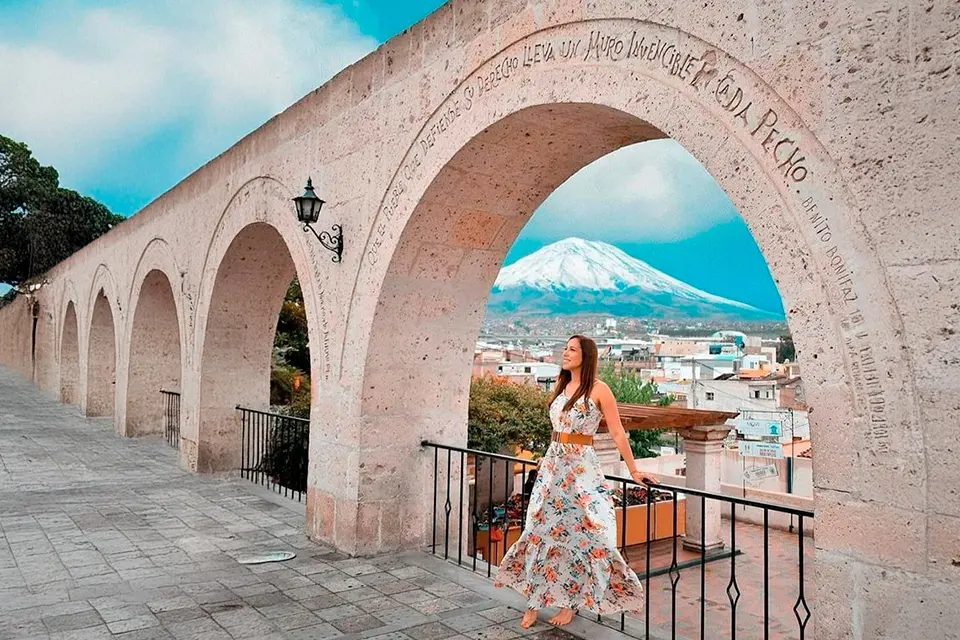 A visitor looking through a sillar arch at Yanahuara towards Misti