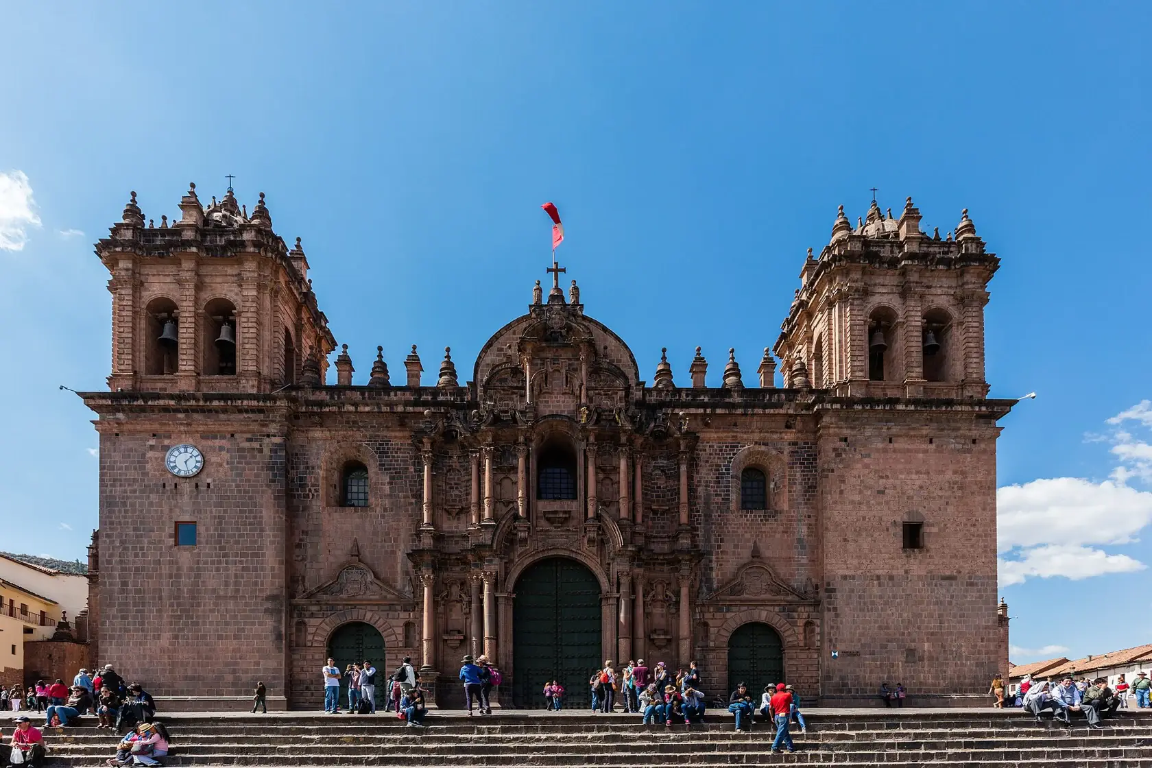 Cusco Cathedral’s two stone bell towers and carved façade facing people in the Plaza de Armas.