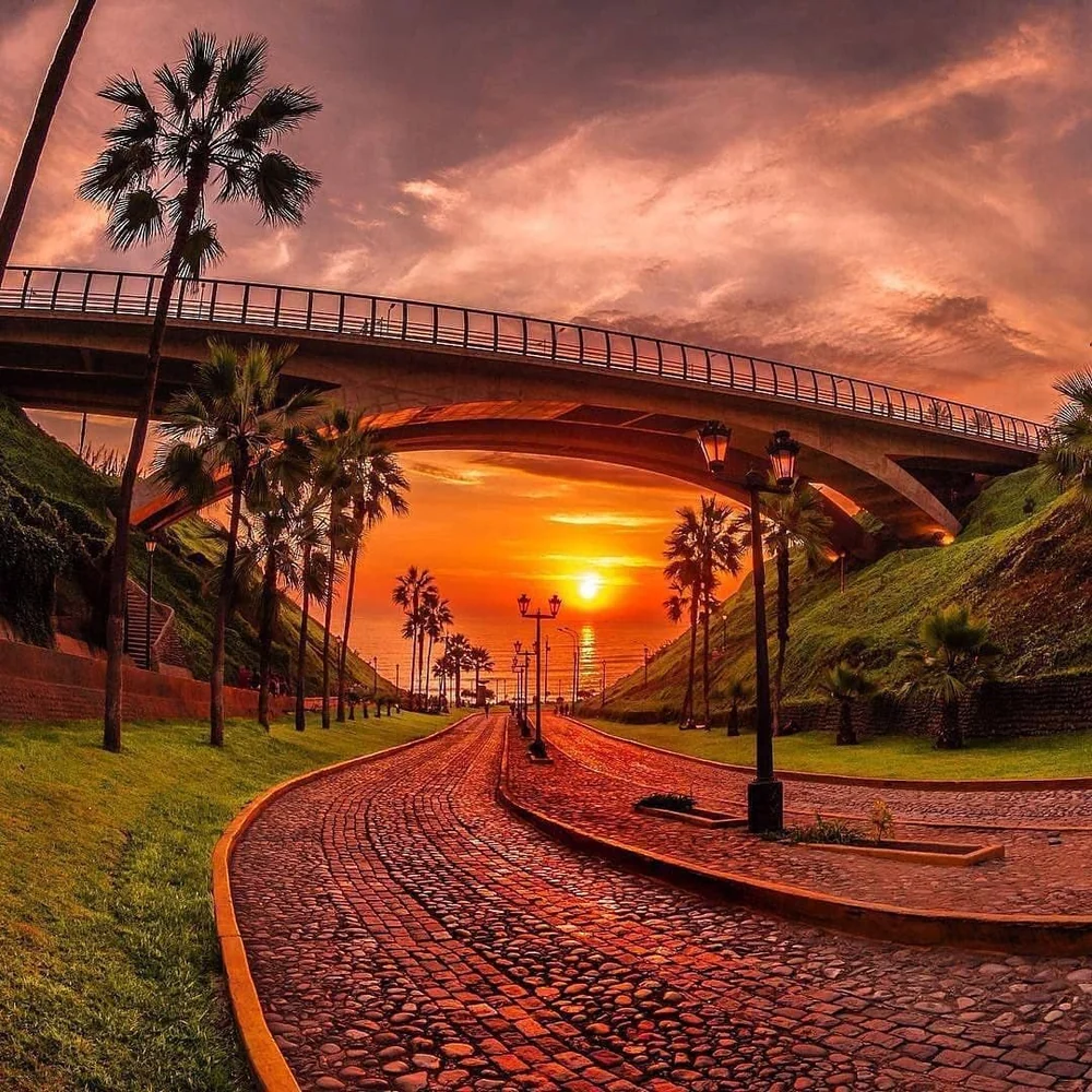 Sunset framed by the bridge and palm-lined path in Miraflores