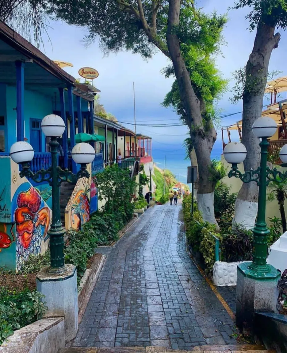 The tree-lined Bajada de Baños, between painted buildings